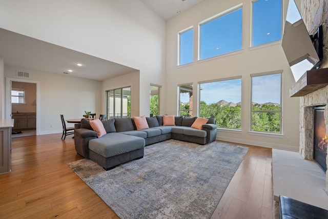 4628 Vieste Vw, Leander, TX 78641 - living area with a warm lit fireplace, light wood finished floors, a high ceiling, and healthy amount of natural light