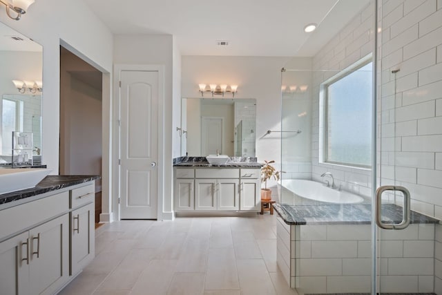 4628 Vieste Vw, Leander, TX 78641 - bathroom featuring two vanities, plenty of natural light, a garden tub, and a shower stall