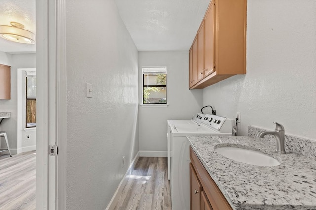 4003 Park Dr, Round Rock, TX 78681 - laundry area featuring washer and dryer, light wood-type flooring, a textured wall, and cabinet space