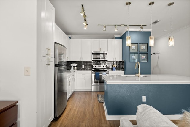 1900 Barton Springs Rd Unit 3038, Austin, TX 78704 - kitchen with appliances with stainless steel finishes, backsplash, wood finished floors, white cabinets, and pendant lighting