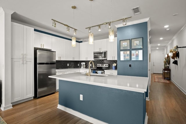 1900 Barton Springs Rd Unit 3038, Austin, TX 78704 - kitchen featuring appliances with stainless steel finishes, backsplash, white cabinets, light countertops, and an island with sink