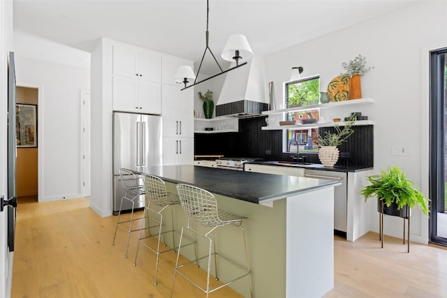4911 Duval, Austin, TX 78751 - kitchen with appliances with stainless steel finishes, open shelves, dark countertops, a kitchen breakfast bar, and white cabinets