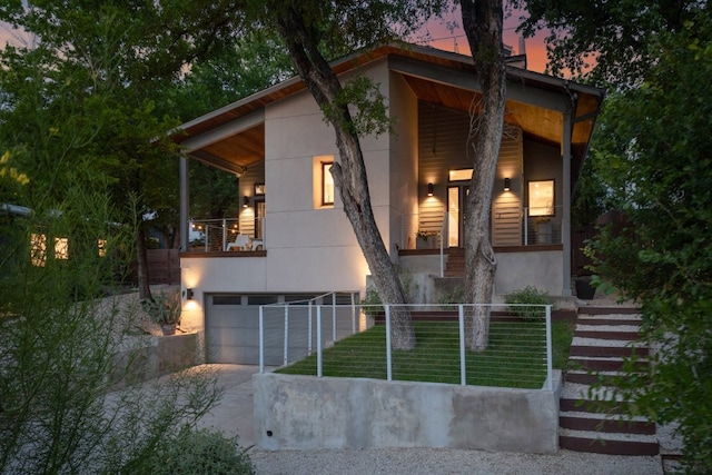 1303 Deloney St, Austin, TX 78721 - contemporary house featuring stucco siding, driveway, a balcony, stairs, and an attached garage