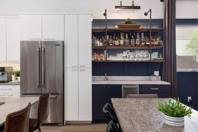1303 Deloney St, Austin, TX 78721 - kitchen featuring high end fridge, light wood finished floors, and white cabinetry