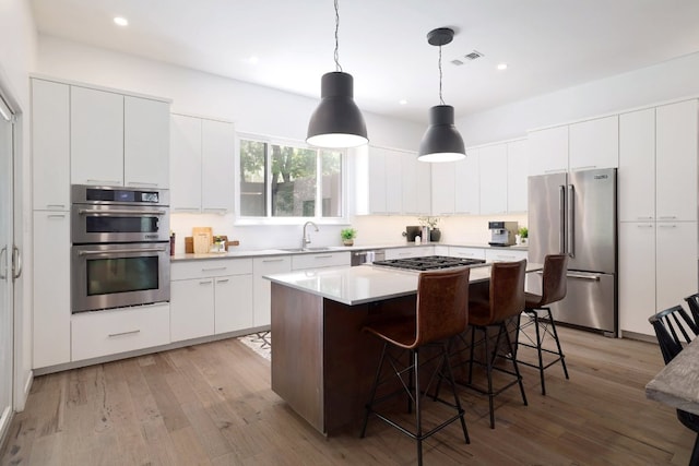 1303 Deloney St, Austin, TX 78721 - kitchen featuring appliances with stainless steel finishes, a kitchen bar, light wood-style flooring, a kitchen island, and recessed lighting