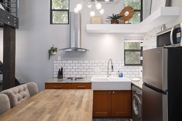 1305 Deloney St, Austin, TX 78721 - kitchen with appliances with stainless steel finishes, brown cabinets, washer / clothes dryer, range hood, and decorative backsplash