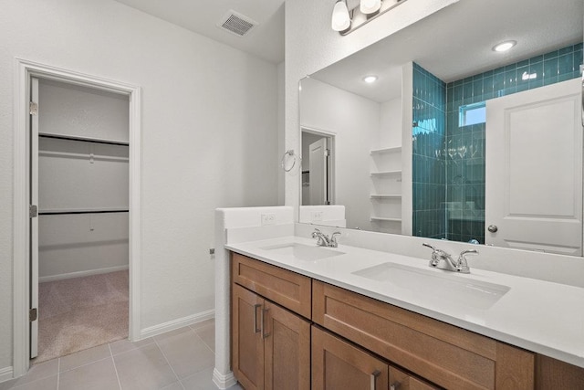 13228 Ditka Dr, Austin, TX 78652 - bathroom featuring a walk in closet, double vanity, tile patterned flooring, and tiled shower