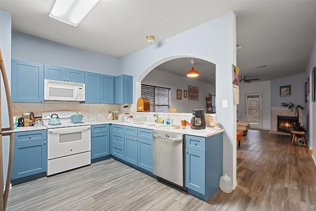 9206 Brents Elm Dr, Austin, TX 78744 - kitchen featuring white appliances, blue cabinetry, light wood-type flooring, a lit fireplace, and light countertops