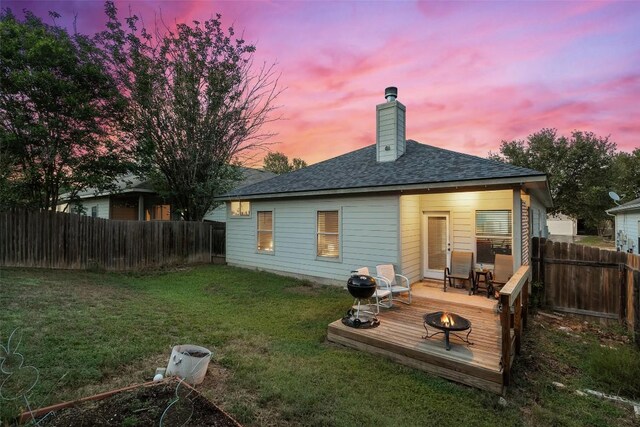 9206 Brents Elm Dr, Austin, TX 78744 - back of property at dusk with an outdoor fire pit, a fenced backyard, a deck, and a chimney