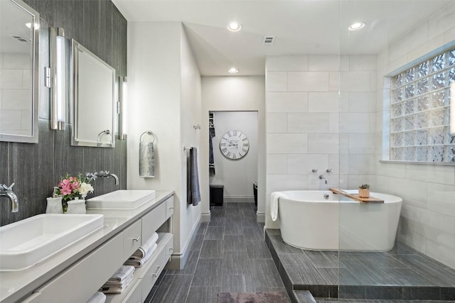 15908 Spillman Ranch Loop, Austin, TX 78738 - full bath with double vanity, a freestanding tub, recessed lighting, and tile walls