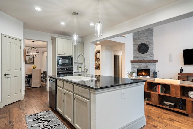 15908 Spillman Ranch Loop, Austin, TX 78738 - kitchen featuring black appliances, dark countertops, dark wood finished floors, a center island with sink, and open floor plan