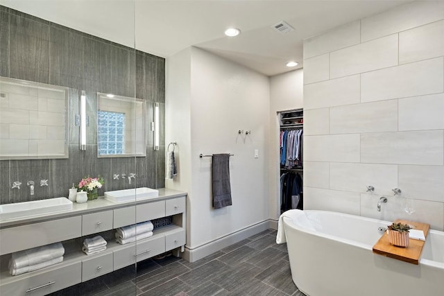 15908 Spillman Ranch Loop, Austin, TX 78738 - full bathroom featuring double vanity, a soaking tub, a spacious closet, recessed lighting, and tile walls