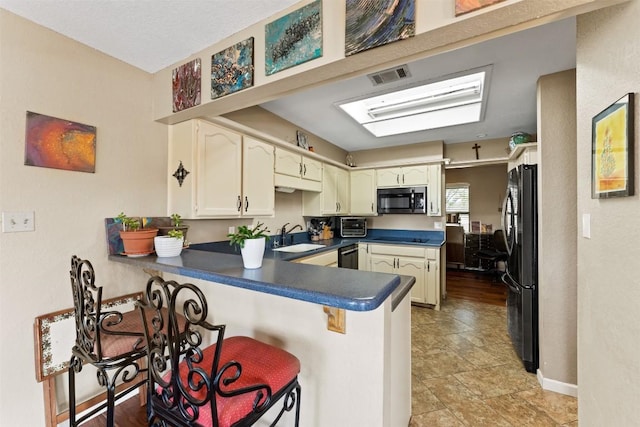 21013 Ridgeview Loop, Lago Vista, TX 78645 - kitchen featuring black appliances, a peninsula, dark countertops, and a kitchen bar