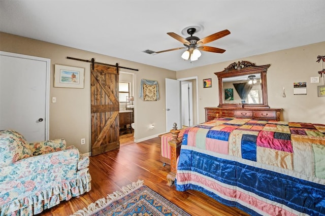 21013 Ridgeview Loop, Lago Vista, TX 78645 - bedroom featuring a barn door, wood finished floors, a ceiling fan, and ensuite bathroom
