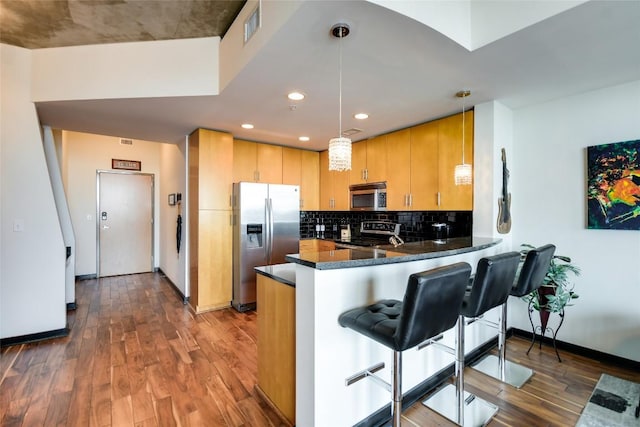 360 Nueces St Unit 3807, Austin, TX 78701 - kitchen featuring appliances with stainless steel finishes, dark wood-style flooring, a peninsula, decorative backsplash, and recessed lighting