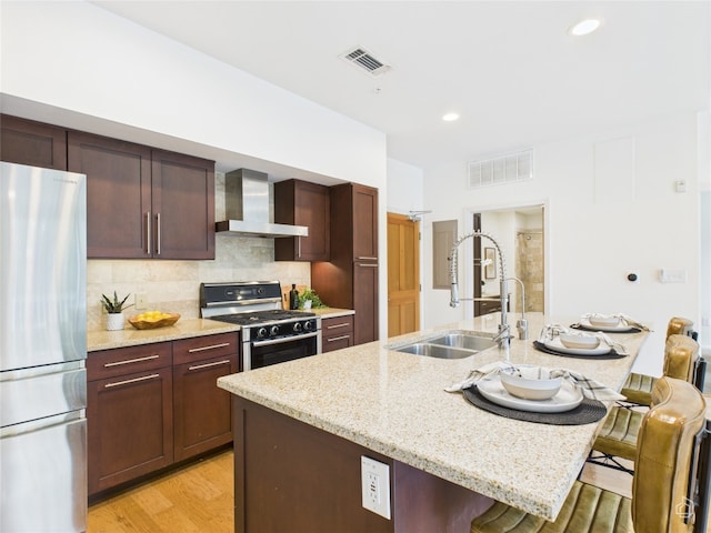 1600 Barton Springs Rd Unit 5107, Austin, TX 78704 - kitchen featuring freestanding refrigerator, gas range, wall chimney exhaust hood, a breakfast bar area, and recessed lighting
