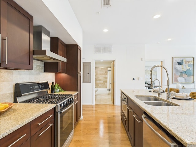 1600 Barton Springs Rd Unit 5107, Austin, TX 78704 - kitchen with appliances with stainless steel finishes, wall chimney range hood, light wood-style flooring, decorative backsplash, and light stone countertops