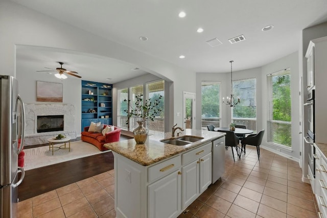 7617 Roaring Springs Dr, Austin, TX 78736 - kitchen with stainless steel appliances, a premium fireplace, light tile patterned flooring, white cabinetry, and open floor plan