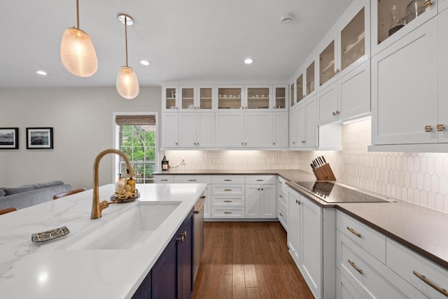 509 Explorer Dr, Lakeway, TX 78734 - kitchen featuring black electric stovetop, white cabinetry, decorative backsplash, pendant lighting, and dark wood-style flooring