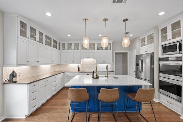 509 Explorer Dr, Lakeway, TX 78734 - kitchen featuring stainless steel appliances, a kitchen island with sink, decorative backsplash, a kitchen bar, and recessed lighting