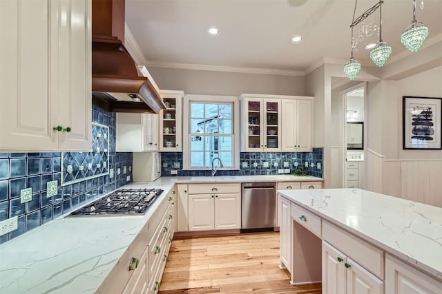 7503 Stonecliff Cir, Austin, TX 78731 - kitchen with appliances with stainless steel finishes, ventilation hood, decorative light fixtures, crown molding, and light stone countertops