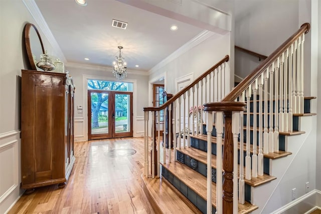 7503 Stonecliff Cir, Austin, TX 78731 - entrance foyer with french doors, stairs, a chandelier, light wood finished floors, and a decorative wall
