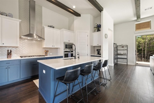 147 William Hersee Dr, Bastrop, TX 78602 - kitchen featuring beamed ceiling, tasteful backsplash, wall chimney range hood, light countertops, and a breakfast bar