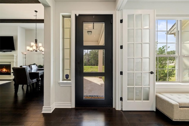 147 William Hersee Dr, Bastrop, TX 78602 - foyer with a chandelier, a warm lit fireplace, and dark wood-style flooring