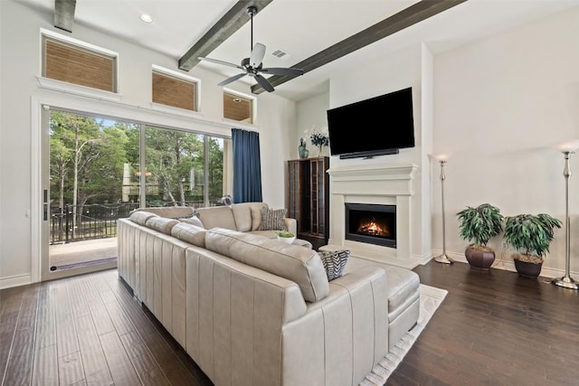 147 William Hersee Dr, Bastrop, TX 78602 - living room with beamed ceiling, dark wood-type flooring, a lit fireplace, and ceiling fan