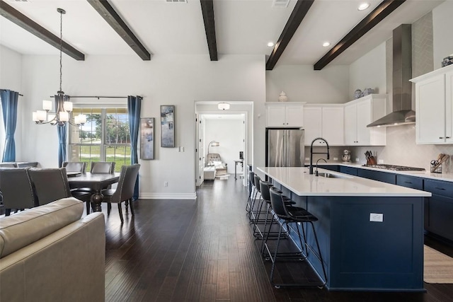 147 William Hersee Dr, Bastrop, TX 78602 - kitchen featuring wall chimney range hood, stainless steel appliances, a chandelier, light countertops, and beamed ceiling