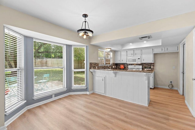 907 Great Oaks Cv, Round Rock, TX 78681 - kitchen featuring white microwave, range, light wood finished floors, a peninsula, and tasteful backsplash
