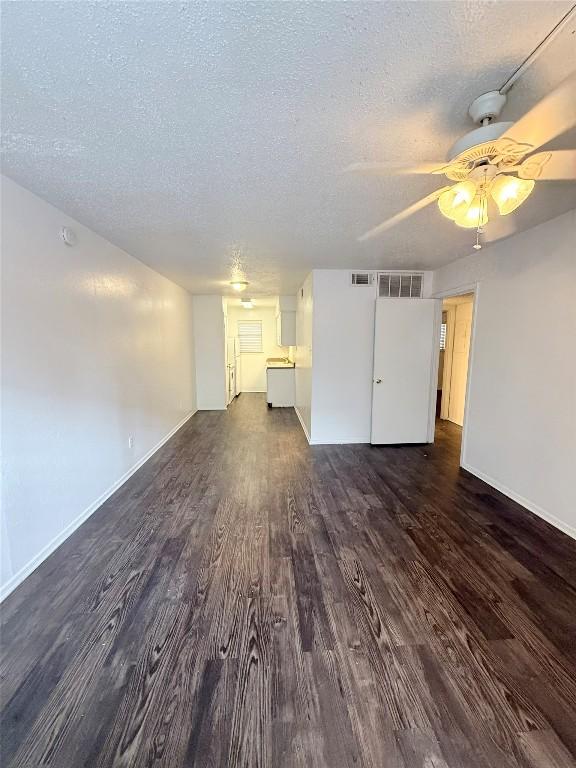 2704 Salado St Unit 207, Austin, TX 78705 - unfurnished living room featuring dark wood-style flooring, a textured ceiling, and a ceiling fan