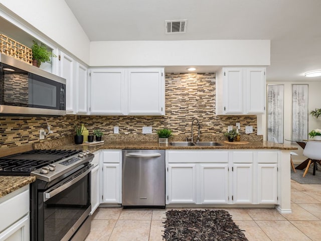12919 Margit Dr, Austin, TX 78729 - kitchen with appliances with stainless steel finishes, white cabinetry, light tile patterned floors, and backsplash