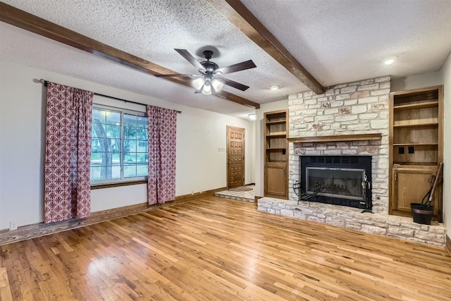 6819 Bayridge Ter, Austin, TX 78759 - unfurnished living room featuring a textured ceiling, beamed ceiling, light wood-style floors, a fireplace, and a ceiling fan