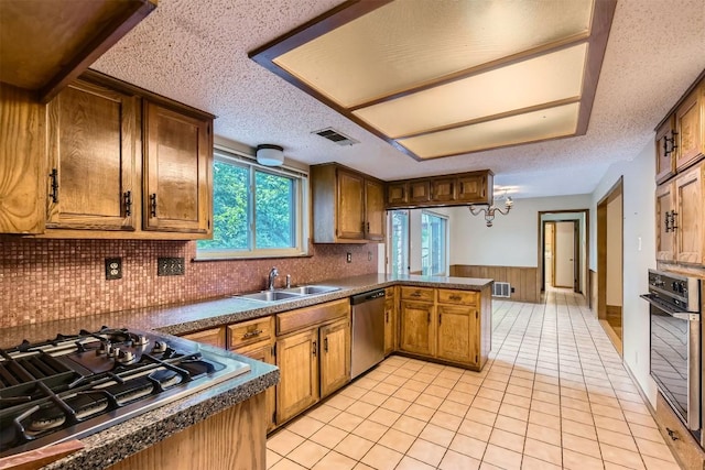 6819 Bayridge Ter, Austin, TX 78759 - kitchen featuring stainless steel appliances, a peninsula, dark countertops, decorative backsplash, and a textured ceiling