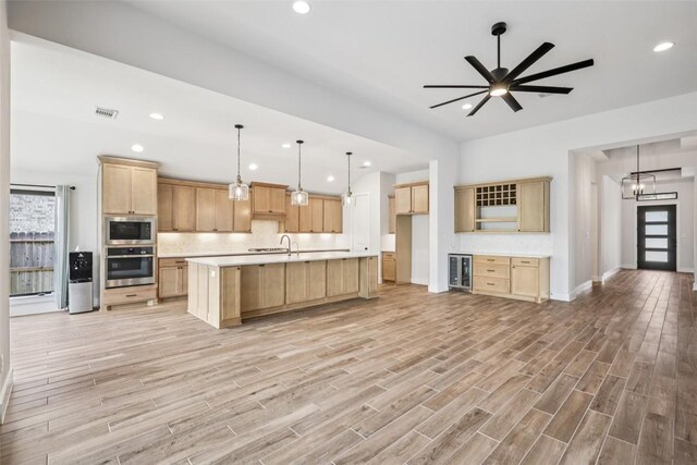 412 Pin Cherry Pass, San Marcos, TX 78666 - kitchen with stainless steel appliances, light brown cabinetry, wine cooler, light countertops, and tasteful backsplash