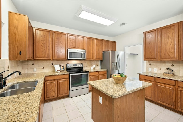 11024 Mint Julep Dr, Austin, TX 78748 - kitchen with stainless steel appliances, tasteful backsplash, light tile patterned floors, a kitchen island, and brown cabinets