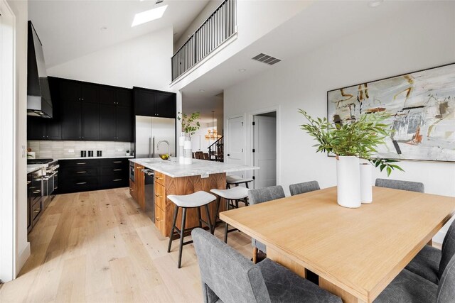 3901 Peak Lookout Dr, Austin, TX 78738 - dining space featuring light wood-style floors, a skylight, and a high ceiling