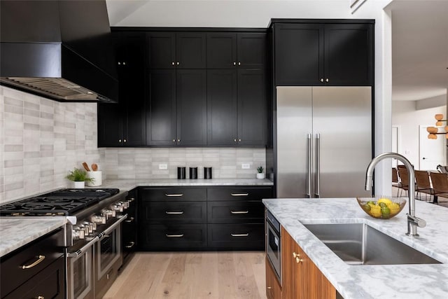 3901 Peak Lookout Dr, Austin, TX 78738 - kitchen with wall chimney exhaust hood, premium appliances, light stone counters, and light wood-type flooring