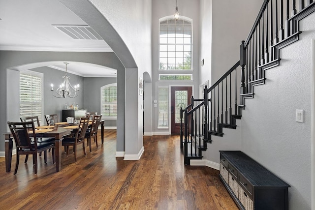 15413 Echo Hills Dr, Austin, TX 78717 - entrance foyer with dark wood-style floors, arched walkways, a chandelier, crown molding, and stairway