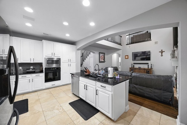 15413 Echo Hills Dr, Austin, TX 78717 - kitchen featuring black appliances, arched walkways, open floor plan, light tile patterned floors, and white cabinets