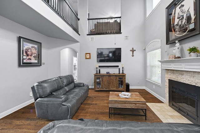 15413 Echo Hills Dr, Austin, TX 78717 - living room featuring arched walkways, wood finished floors, a stone fireplace, and a high ceiling