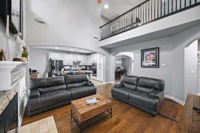 15413 Echo Hills Dr, Austin, TX 78717 - living area featuring arched walkways, a high ceiling, a fireplace, and wood finished floors
