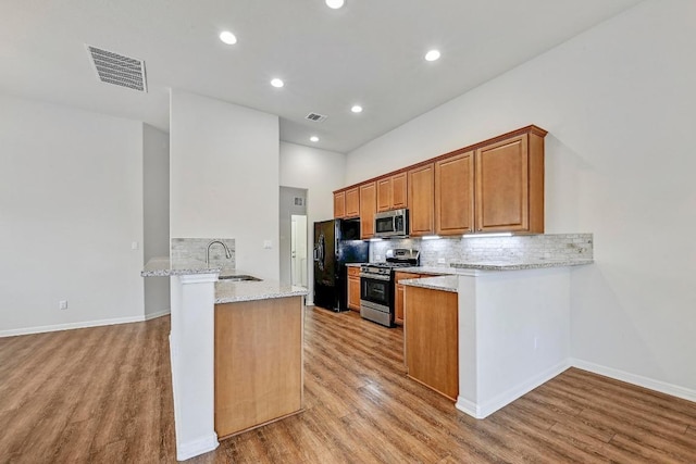 2344 Broken Wagon Dr, Leander, TX 78641 - kitchen with appliances with stainless steel finishes, a peninsula, light wood-type flooring, tasteful backsplash, and recessed lighting