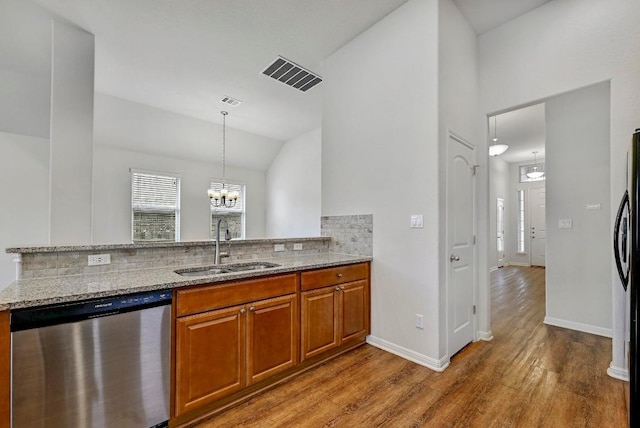 2344 Broken Wagon Dr, Leander, TX 78641 - kitchen with stainless steel dishwasher, light stone counters, brown cabinets, wood finished floors, and backsplash