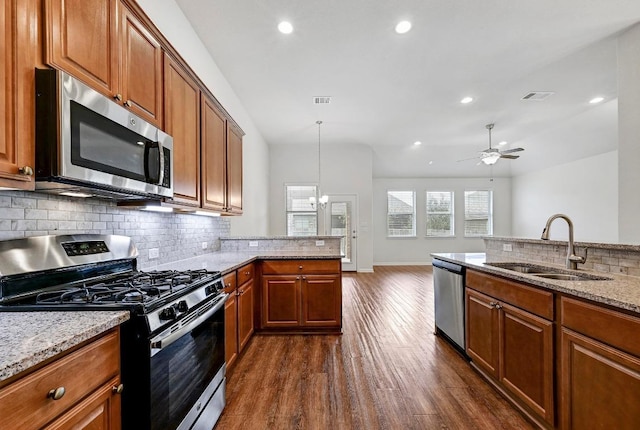2344 Broken Wagon Dr, Leander, TX 78641 - kitchen featuring stainless steel appliances, backsplash, dark wood-style flooring, brown cabinets, and recessed lighting