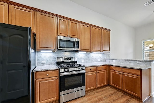 2344 Broken Wagon Dr, Leander, TX 78641 - kitchen with appliances with stainless steel finishes, brown cabinets, and a peninsula