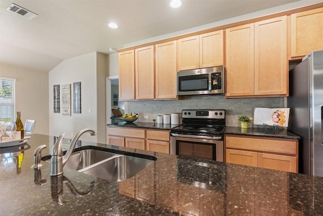 19105 Obed River Dr, Pflugerville, TX 78660 - kitchen with appliances with stainless steel finishes, light brown cabinets, backsplash, vaulted ceiling, and dark stone countertops