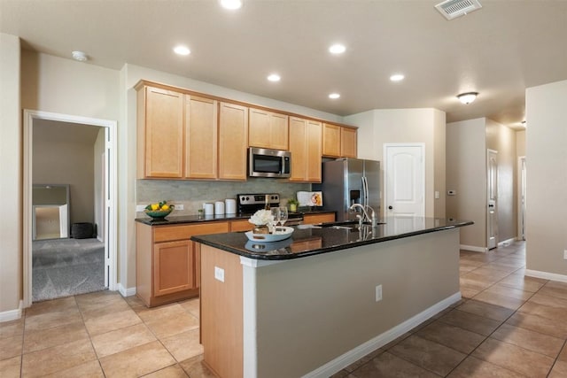 19105 Obed River Dr, Pflugerville, TX 78660 - kitchen featuring appliances with stainless steel finishes, a kitchen island with sink, light tile patterned floors, light brown cabinets, and recessed lighting