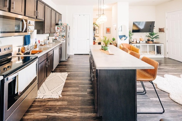 8601 W Gate Blvd Unit 4103, Austin, TX 78745 - kitchen featuring stainless steel appliances, a kitchen island, a breakfast bar area, dark wood-style flooring, and dark brown cabinets